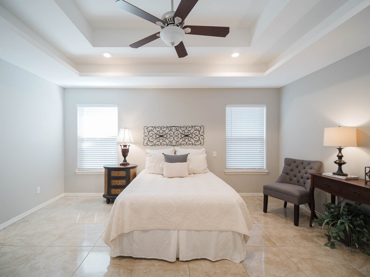 A bedroom with a bed, chair and ceiling fan.