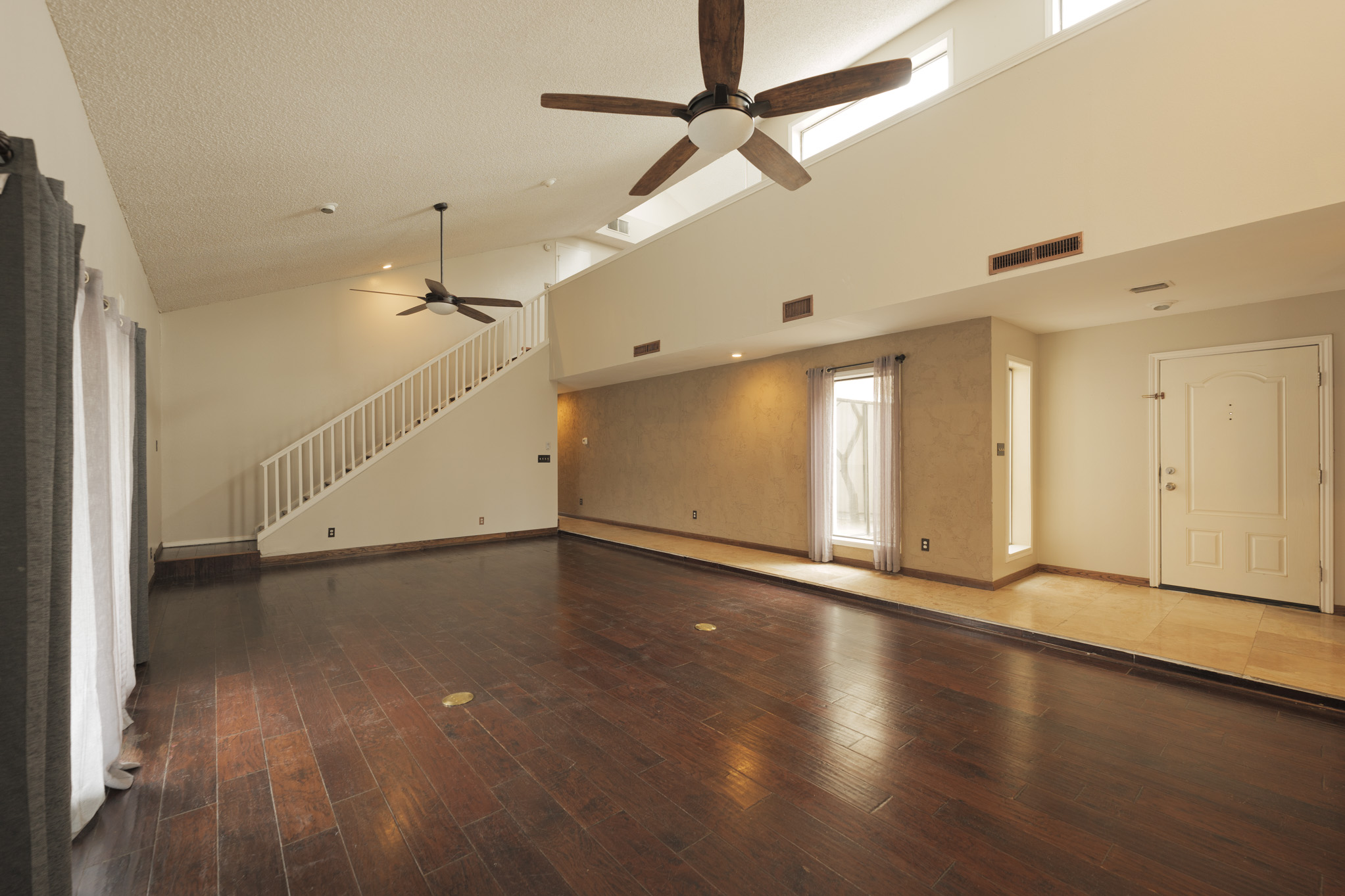 A large room with hard wood floors and ceiling fans.