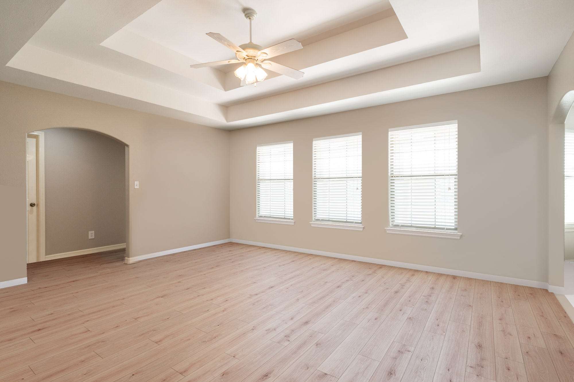 A room with three windows and a ceiling fan.