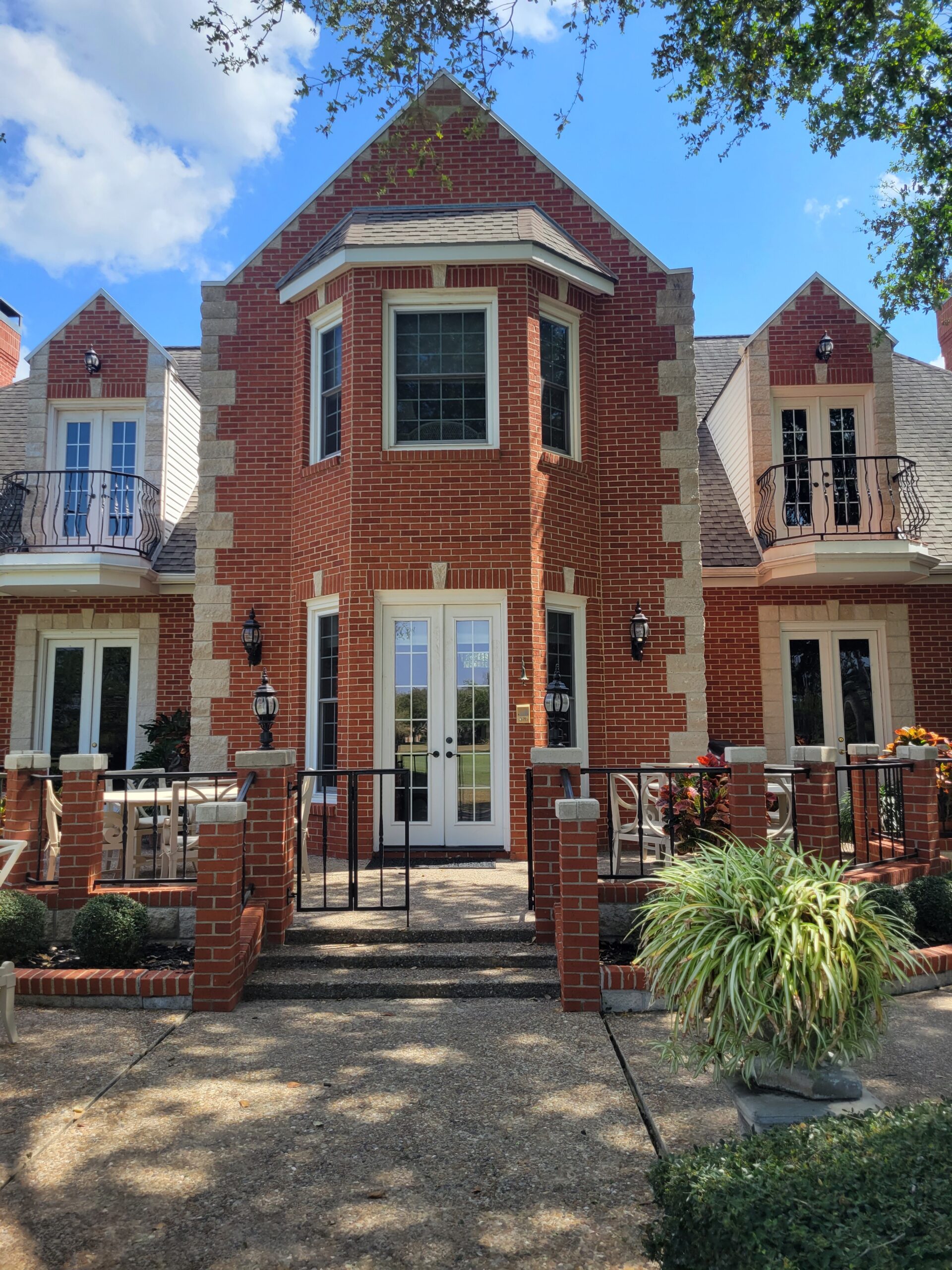 A large brick house with a balcony and a porch.