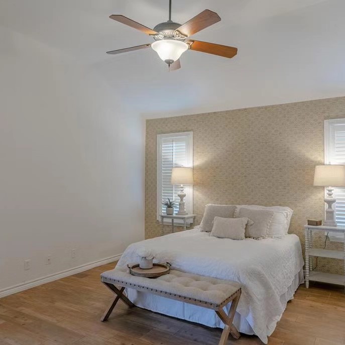 A bedroom with a bed, two lamps and a bench.